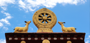 Roda Dharma diapit dua rusa dengan latar langit biru, lambang pembabaran Dharma